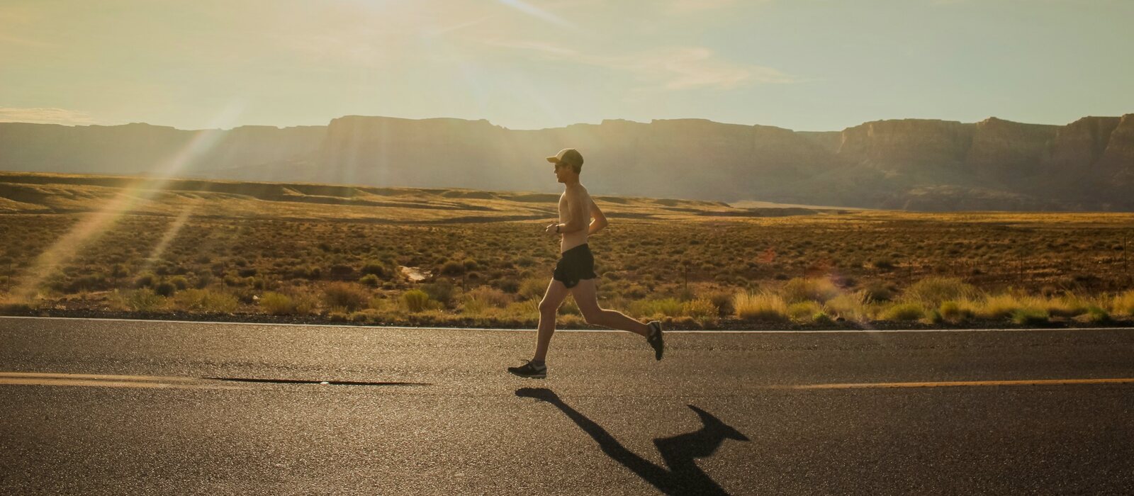 man in black shorts running on gray asphalt road during daytime