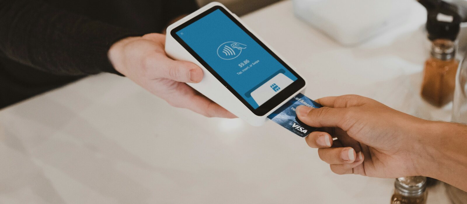 person putting magstripe card near black card terminal