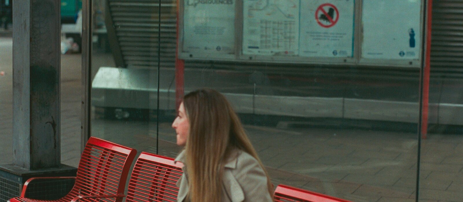 Woman sits on red bench at vauxhall station