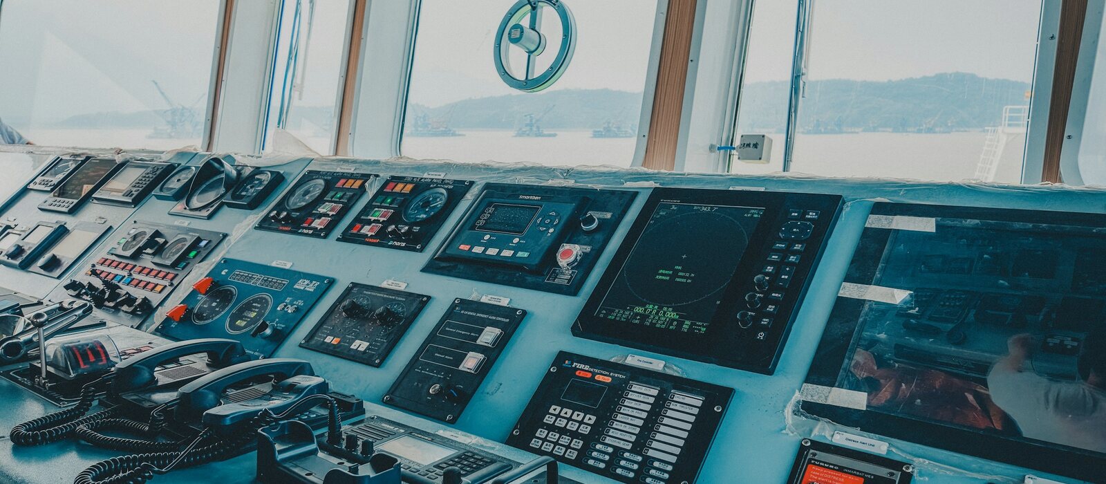 Ship bridge control console with navigation screens and telephones